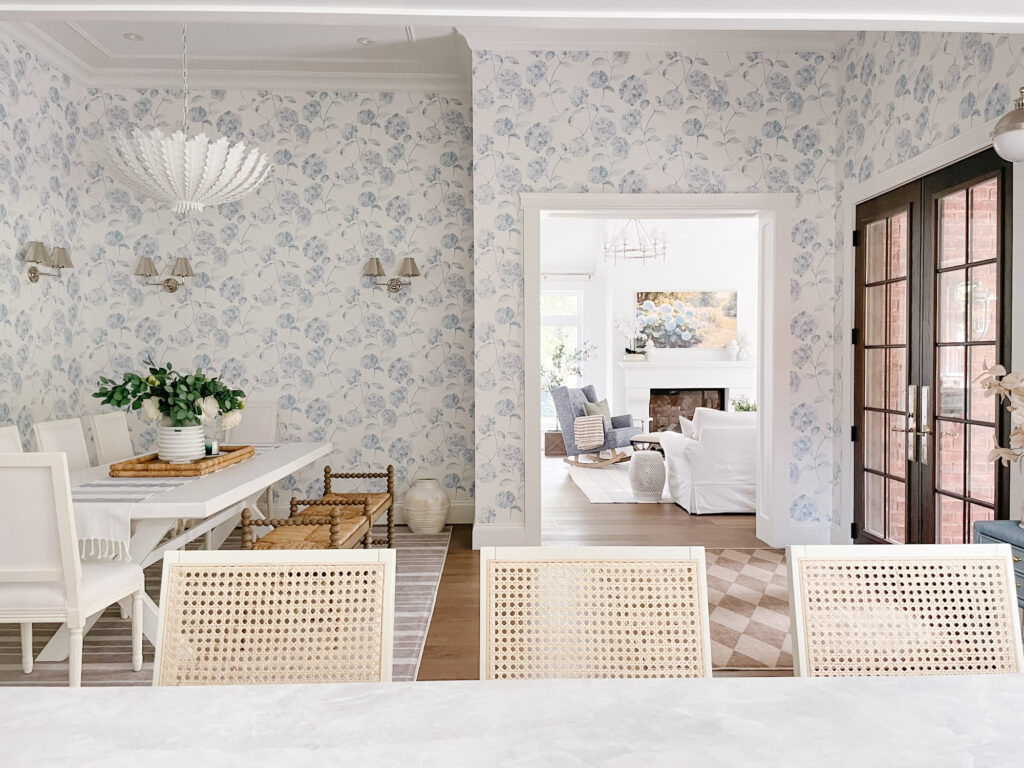 View into white living room through blue hydrangea wallpapered dining room
